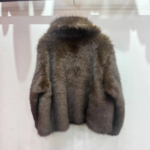 Veste courte en fausse fourrure marron avec texture pelucheuse sur un mur blanc
