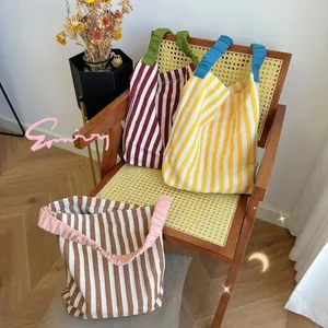 Detail of colorful striped canvas tote bags featuring unique ruffled elastic handles