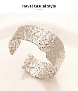 Macro detail of irregular silver hammer-textured cuff bracelet on a white tray
