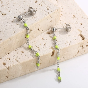 Silver tassel drop earrings with vibrant neon green beads on a minimalist stone background