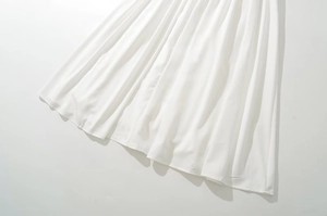 Detailed close-up of white flowing dress hem with elegant lace stitching and soft drapes