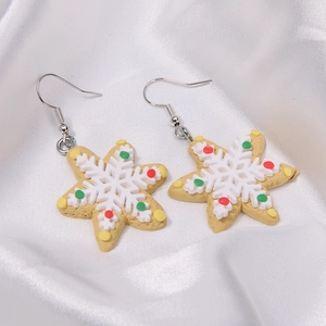 Macro shot of snowflake gingerbread cookie earrings on white silk fabric background