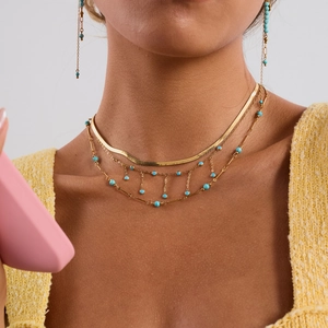 Détail de collier à double rangée doré avec perles turquoise et boucles d'oreilles assorties