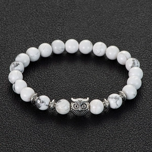 Macro view of white stone beads bracelet featuring a silver vintage owl charm and spacers