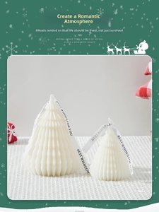 Detail view of two off-white origami Christmas tree candles with best wishes ribbons