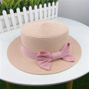 Detailed texture of pink straw sun hat with a striped bow ribbon on a white table