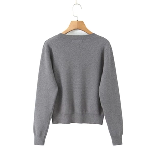 Detail of grey knitted sweater back showing ribbed hem and wooden hanger on white background