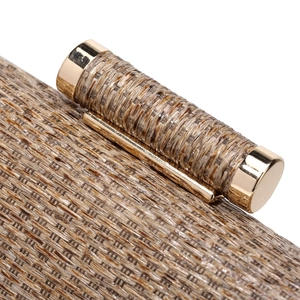 Detail of brown woven straw evening clutch featuring a polished gold cylindrical clasp