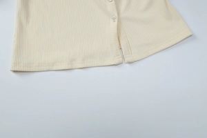 Close-up of ribbed knit texture and white buttons on a beige cardigan set for women