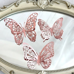 Close-up of three rose gold laser-cut butterflies on a mirror for cake decoration