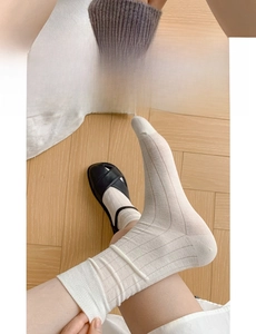 Detail of white ribbed cotton socks featuring a wide elastic cuff and retro black sandals
