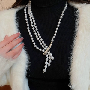 Detail of multi-layer pearl necklace with silver metal accents and fringe on a model