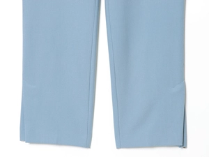 Dettaglio dei pantaloni blu a zampa con spacco laterale e tessuto a trama pregiata
