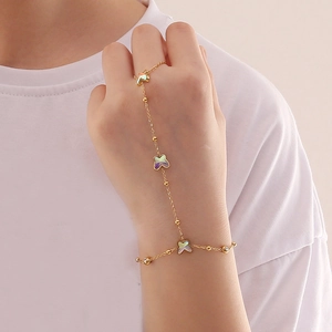 Golden butterfly necklace set and clover hand chain with iridescent finish on a hand