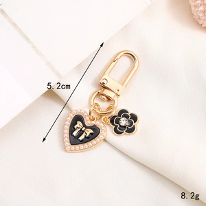 Detailed close-up of a golden keychain featuring a pearl heart and crystal floral pendant