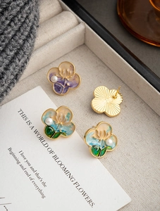Artistic clover earrings with colorful enamel flowers and pearls in a jewelry box