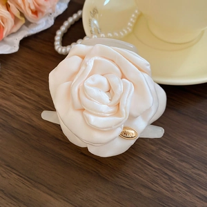 Dettaglio del fermaglio per capelli con rosa di raso e targa LOVE dorata su legno