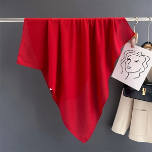 Macro view of solid red linen scarf showing soft fabric texture and drape on a hanger
