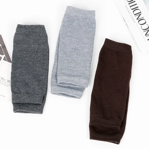 Close-up of three pairs of knit arm warmers in dark grey, light grey, and brown colors