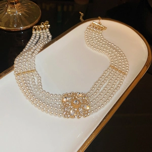 Detailed view of multilayer pearl necklace with gold diamond clasp on luxury tray