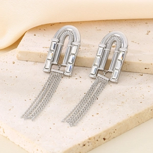 Détail de boucles d'oreilles à pompons argentés avec cristaux rectangulaires sur pierre