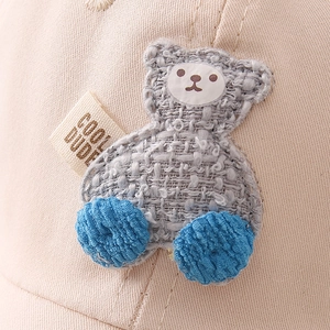 Beige kids baseball cap with woven bear patch and Cool Dude tag detail view