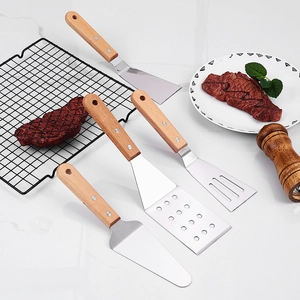 Set of 4 stainless steel cooking spatulas with beechwood handles on marble counter
