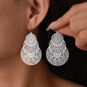 Boucles d'oreilles pendantes fleurs évidées en argent portées par un mannequin en gros plan