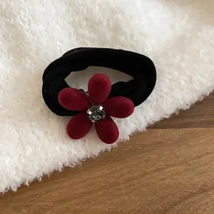 Détail de l'élastique à cheveux avec fleur floquée rouge et diamant brillant au centre