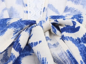 Détail d'une robe tie-dye bleue et blanche avec nœud papillon et dentelle délicate