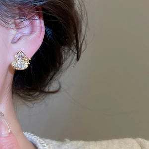 Close-up of gold plated gourd stud earrings with pavé zircons worn on earlobe