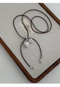 Detailed macro view of vintage silver heart pendants with sparkling zircons on leather cord