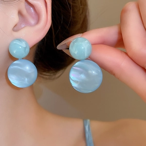 Detail showing light blue double sphere resin earrings with pearlescent marble texture