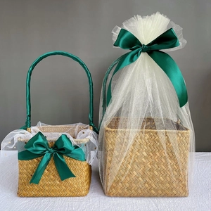Handwoven seagrass gift baskets with green ribbons and white tulle for wedding favors