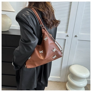 Borsa a spalla in pelle marrone vintage con farfalle argentate indossata da una modella
