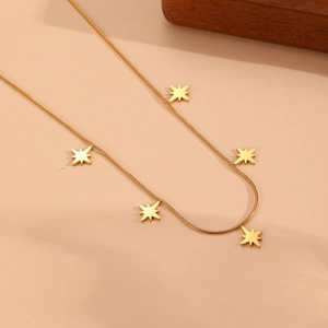 Vue détaillée d'un collier chaîne serpent dorée avec cinq pendentifs d'étoiles polies