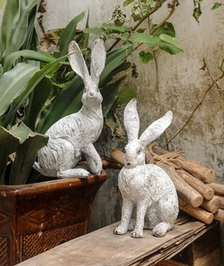 Close-up of vintage resin rabbit statues with antique stone texture for garden decor