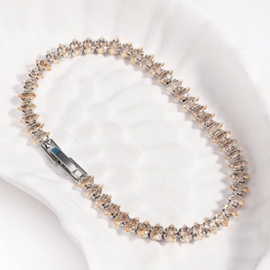 Macro detail of marquise-cut champagne zircons set in a silver tennis bracelet