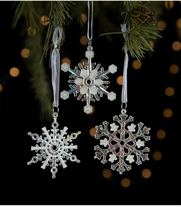 Iridescent snowflake Christmas tree ornaments with white ribbons on pine branches