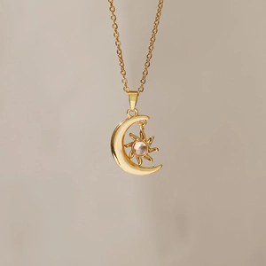 Detailed close-up of golden crescent moon and star pendant necklace with embedded gemstone