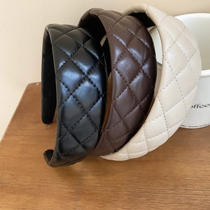 Detailed view of three padded quilted leather headbands in black, brown, and cream tones