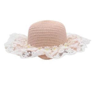 Close-up of pink straw hat with white lace wavy brim and delicate daisy flower decorations