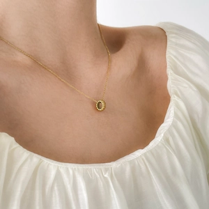 Detailed view of a gold-plated titanium necklace with a textured round charm pendant