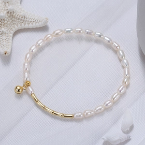 Détail d'un bracelet en perles d'eau douce blanches avec des perles dorées