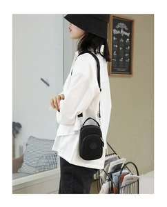 Model wearing a black nylon mini crossbody bag and casual phone pouch over white shirt