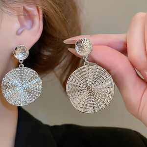Detailed view of silver circular drop earrings featuring a textured woven metal pattern