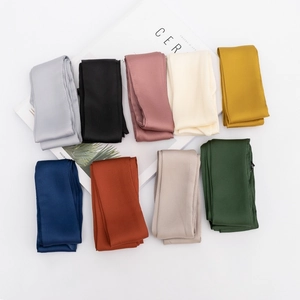 Flat lay of long satin silk scarves in nine elegant colors arranged with a magazine
