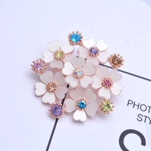 Elegante spilla a fiore con petali bianchi a cuore, strass colorati e base oro rosa