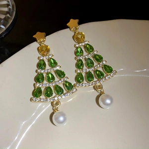 Detailed view of Christmas tree earrings with green stones and hanging white pearls