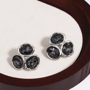 Dettaglio di orecchini a lobo in argento con tre pietre di zircone ovali grigio scuro